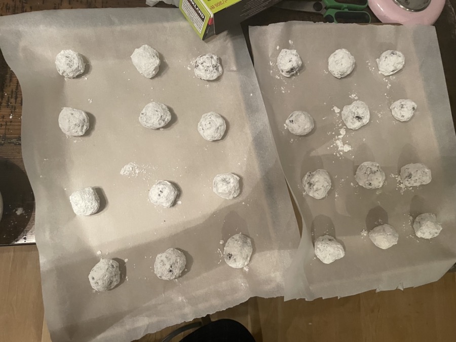 Chocolate crinkle cookie dough balls rolled in powdered sugar, before baking